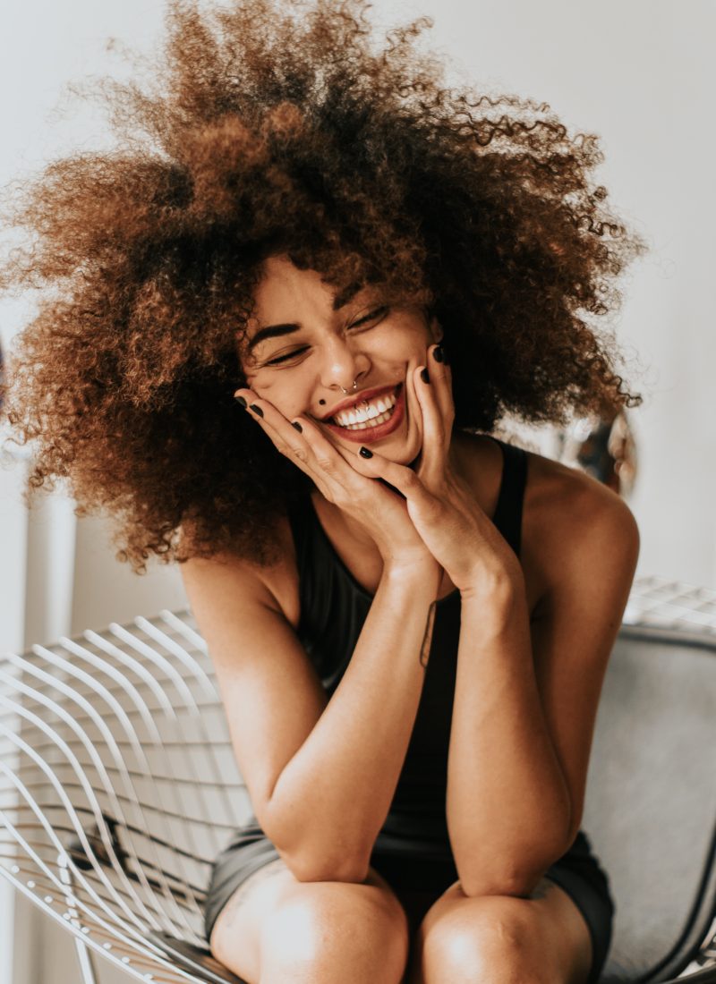 Woman smiling with healthy skin and wild hair.