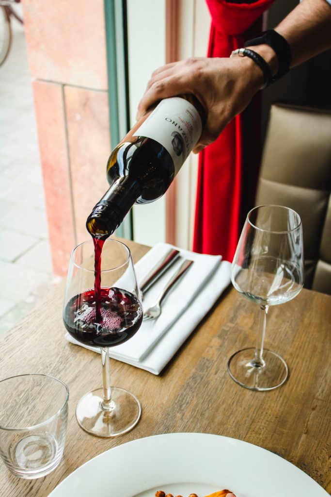 Pouring red wine into glass at restaurant.