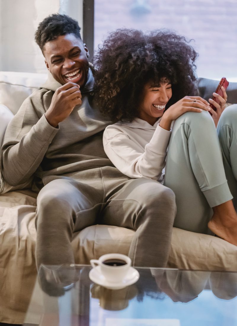 Black couple on couch laughing in love.
